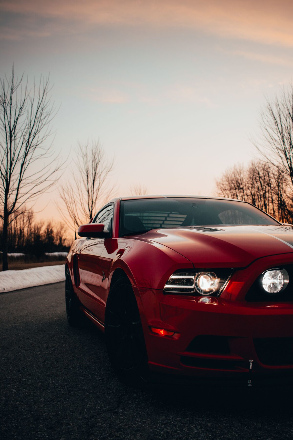 Race Red Mustang GT front three-quarter view, headlights lit