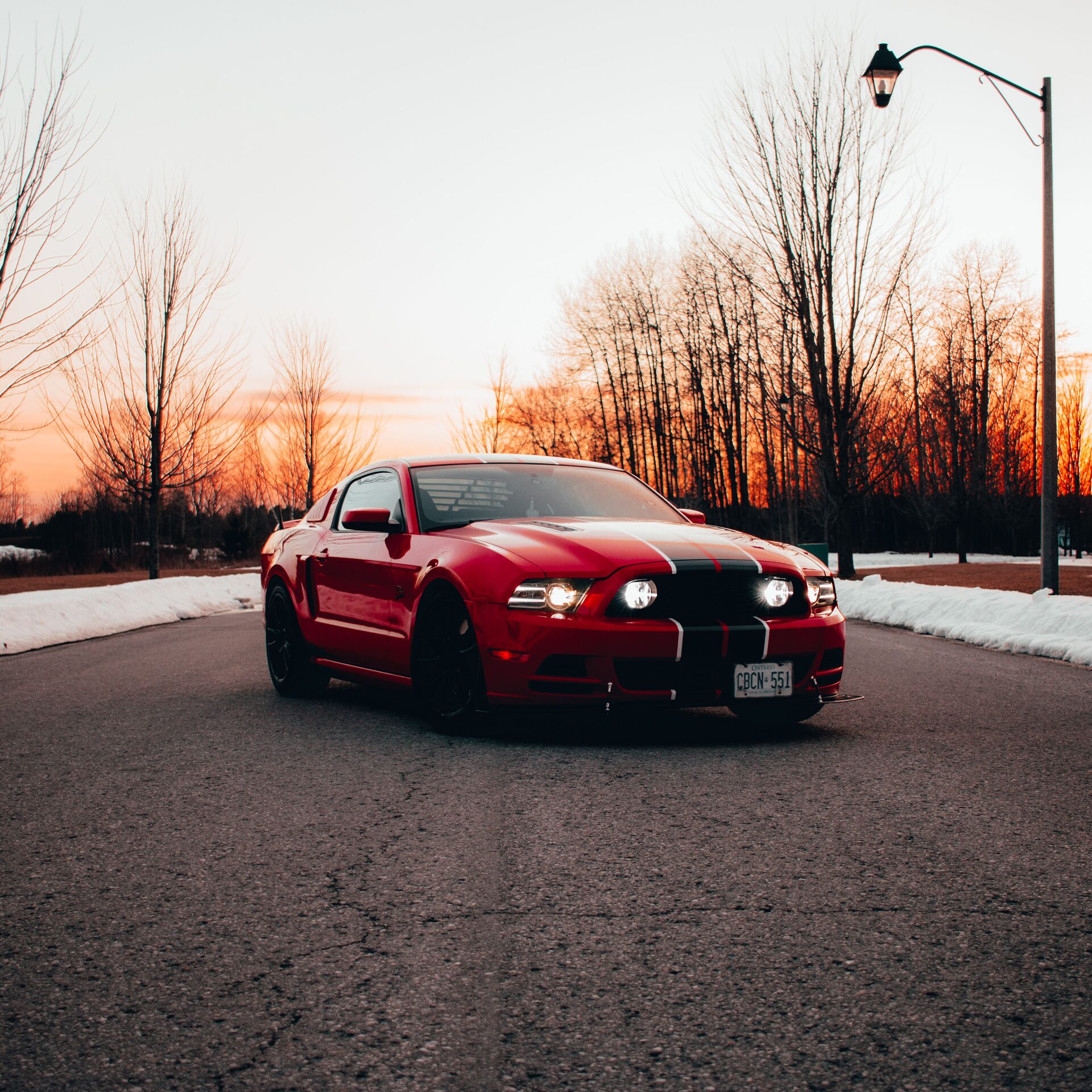 Race Red Ford Mustang GT at winter sunset, headlights on