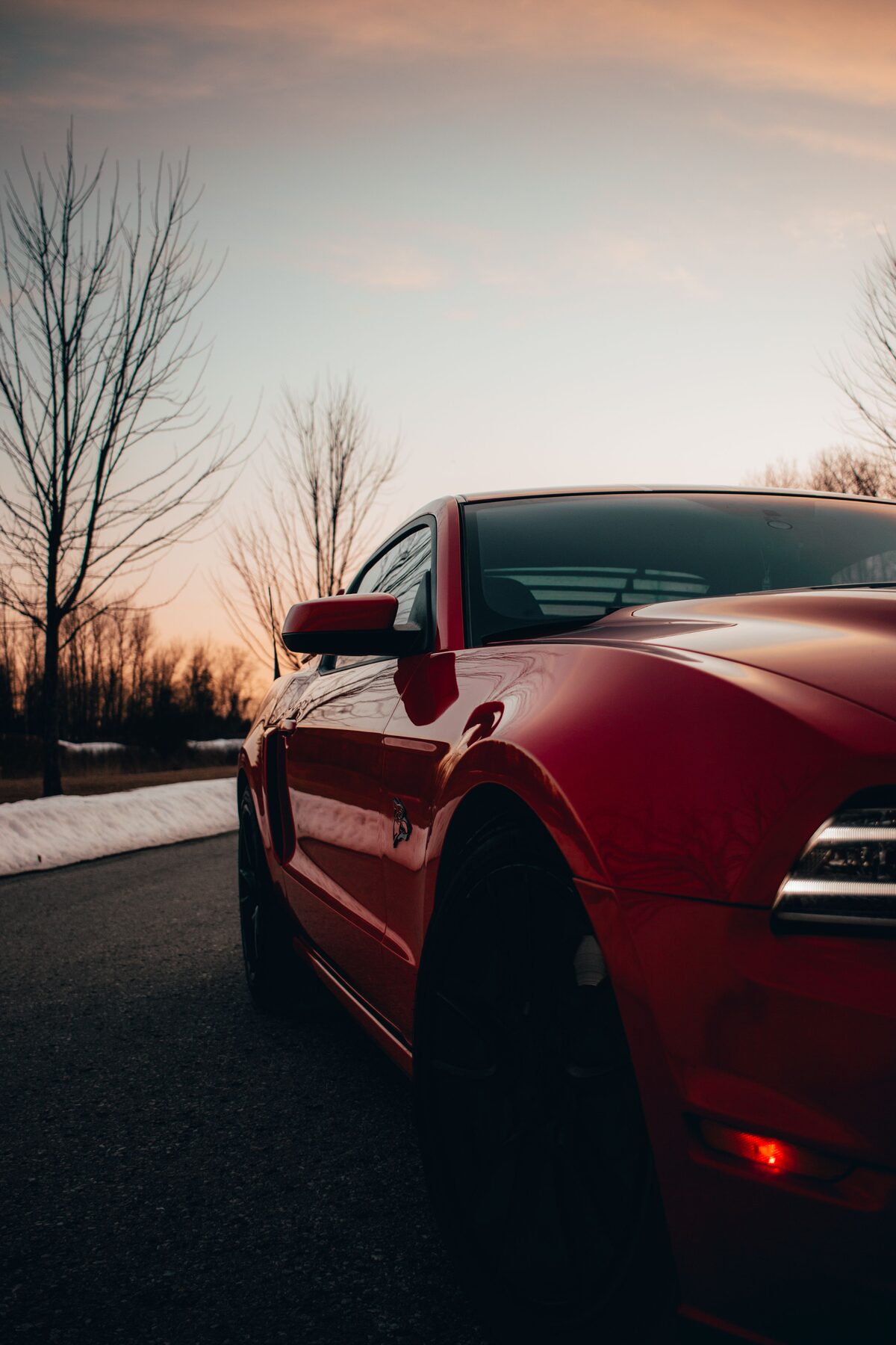 Race Red Mustang GT side profile with black wheels at sunset